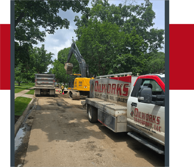 OilWorks bulk fuel truck refueling excavator and dump truck during road construction project.